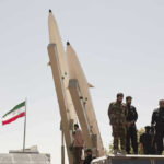 One Word Divides the Debate: ‘Obliterated.’ Military personnel beside missiles and Iranian flag.