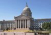 Exterior view of a state capitol building with a dome and flags