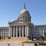 Judge Pauses Work as 250-Foot Arch Sparks National Debate Exterior view of a state capitol building with a dome and flags