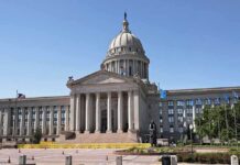 Judge Pauses Work as 250-Foot Arch Sparks National Debate Exterior view of a state capitol building with a dome and flags