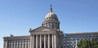 Exterior view of a state capitol building with a dome and flags