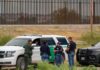 Newly Released Documents Raise Questions About FBI law enforcement officers confer beside patrol vehicles near a border fence