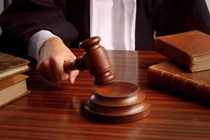 A judges hand holding a gavel over a wooden desk with law books