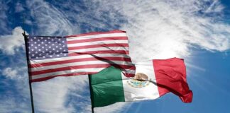 United States and Mexico flags waving against a bright sky