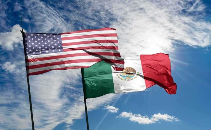 shutterstock_2281651931 United States and Mexico flags waving against a bright sky