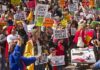 Crowd of protesters holding signs advocating for labor rights and social justice