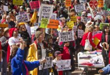 Crowd of protesters holding signs advocating for labor rights and social justice