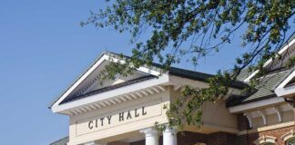 Exterior view of a city hall building with columns and a clear blue sky