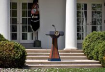 Pentagon Revokes Security Clearance Podium with presidential seal in a garden colonnade