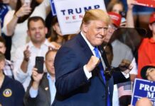 Trump’s Latest Political Weapon: “Communist” man in suit raising fists at a rally podium
