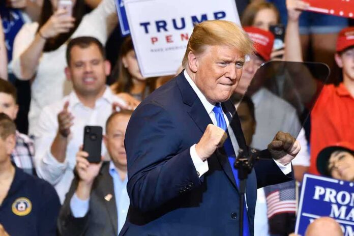 shutterstock_1148319815-1 man in suit raising fists at a rally podium