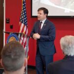 Capitol Protest Turns Into a Military Free-Speech Fight Man in suit speaking at a podium in a conference room