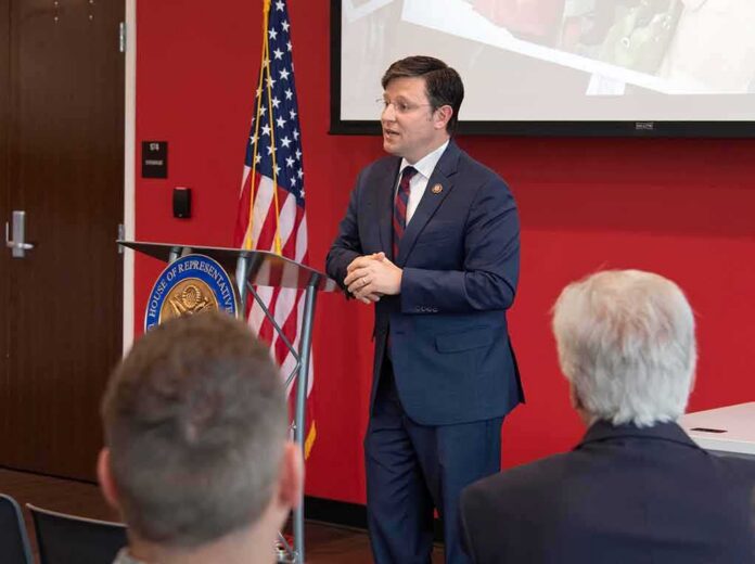 Man in suit speaking at a podium in a conference room