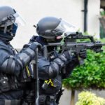 Belfast Riots Expose Rise in Anti-Migrant Hate armed police officers aiming rifles during operation