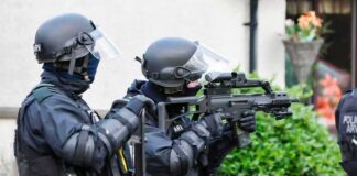 armed police officers aiming rifles during operation