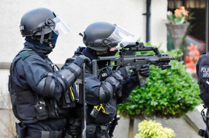 armed police officers aiming rifles during operation