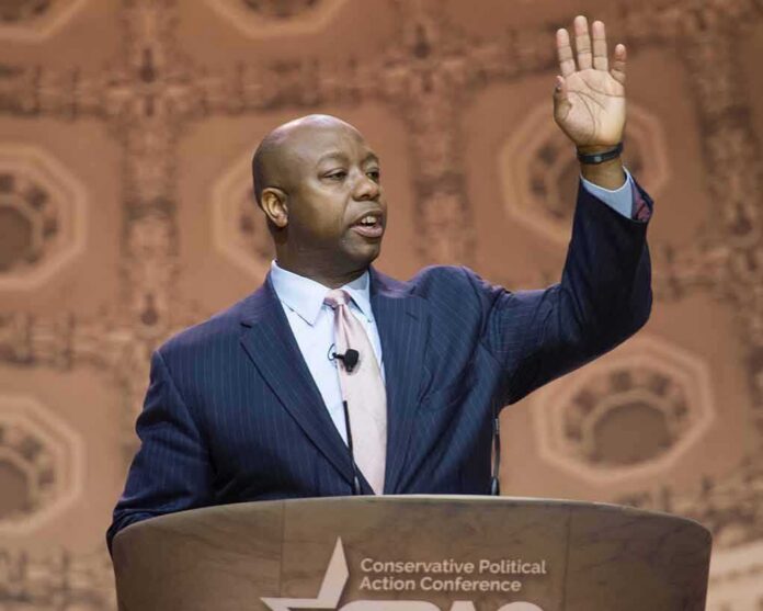 Speaker in suit addressing audience at podium with hand raised