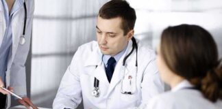 Doctors in white coats discuss patient case at a table