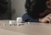 Person with head down near scattered pills on a table