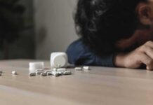 Study Finds Many Students Don’t Recognize Fentanyl’s Danger Person with head down near scattered pills on a table