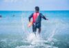 lifeguard wading into ocean with rescue buoy