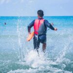 A Father Rushed Into Dangerous Surf to Save a Child. He Paid a Terrible Price. lifeguard wading into ocean with rescue buoy