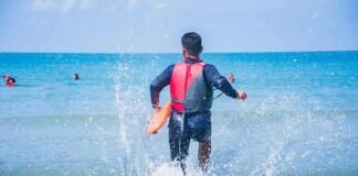 lifeguard wading into ocean with rescue buoy