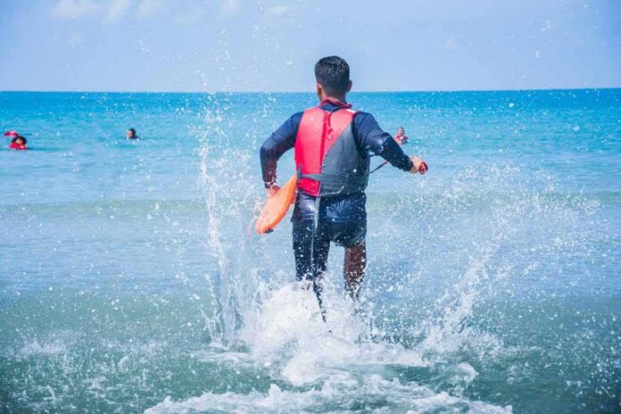 lifeguard wading into ocean with rescue buoy