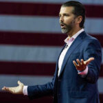 Secret Meeting. Billion-Dollar Promises. Then the Charges Vanished. Donald Trump Jr. speaking on stage with arms outstretched
