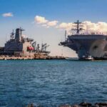 U.S. Forces Sink Alleged Cartel Refueling Vessel Aircraft carrier and support ships docked at a naval harbor