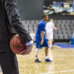 Owner vs. Teens? Arena Meltdown Claims Basketball coach in suit holding ball courtside