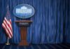 Corporate America’s Millions Fuel Trump’s Agenda White House press briefing podium with U.S. flag and blue curtain