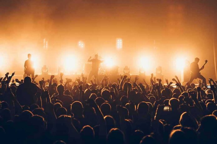 Rock band performing on stage with bright backlights and cheering crowd