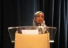 Fraud Claims Face Evidence Test Woman in hijab speaking at a podium