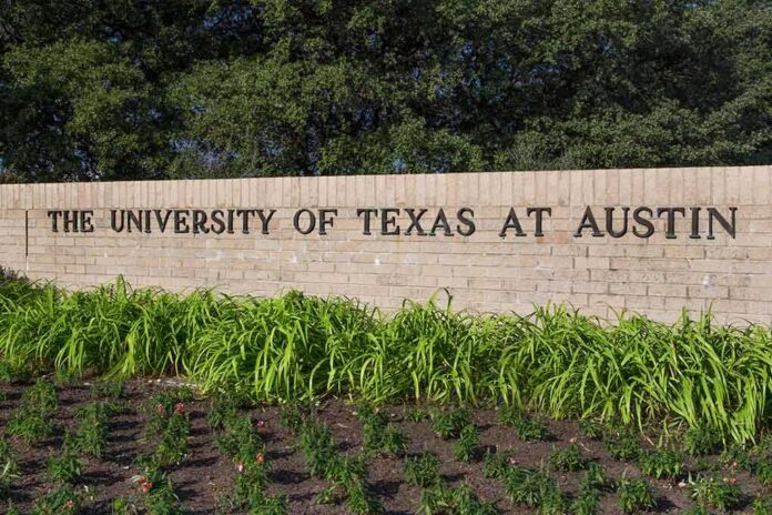 Sign for The University of Texas at Austin surrounded by greenery