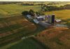 Aerial view of a farm with silos and barns amid golden crop fields
