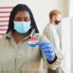 One Endorsement Changed Louisiana’s Senate Race Voter wearing a mask holds an I Voted sticker at a polling place