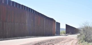 Border wall along a dusty desert road