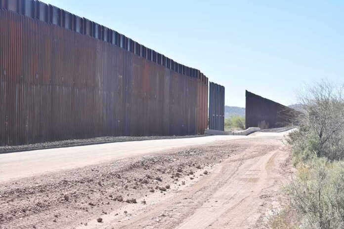shutterstock_1958049433 Border wall along a dusty desert road