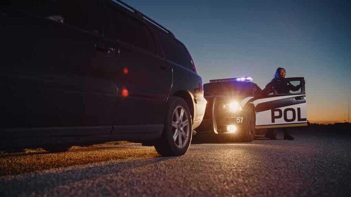 shutterstock_2232055739-2 Police officer at patrol car during traffic stop at dusk