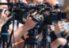 AOC Leaves 2028 Door Open television cameras on tripods at a media event