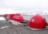 Red dome shelters at a polar research station by the sea