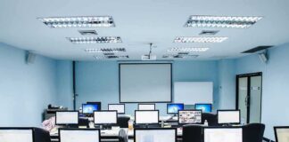 computer lab with rows of monitors facing a projector screen
