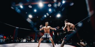 Two MMA fighters square off in a caged octagon