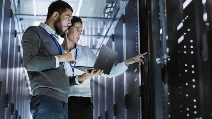shutterstock_661113826 IT technicians inspect server racks in a data center aisle