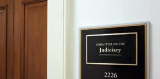 Office sign for judiciary committee beside wooden doors