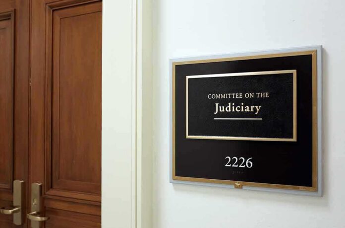 Office sign for judiciary committee beside wooden doors