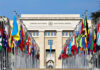 Trump Threatens: Iran Threat Raises Global Tensions United Nations building with numerous national flags outside.