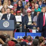Ron DeSantis speaks at a rally podium as Donald Trump stands nearby; Badri Patarkatsishvili in the crowd