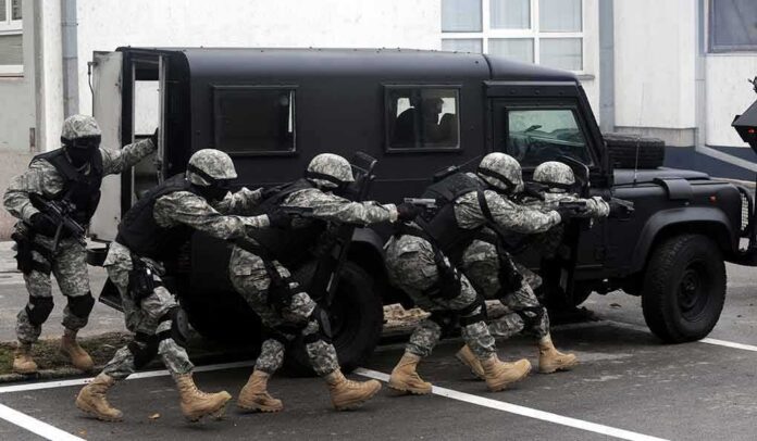 Tactical team advances beside an armored vehicle